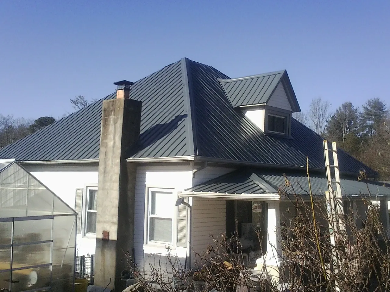 Dark blue standing seam metal roof on a white farmhouse with dormer — Slate & Tile Roof Repair by Roofing Brothers in Adairville