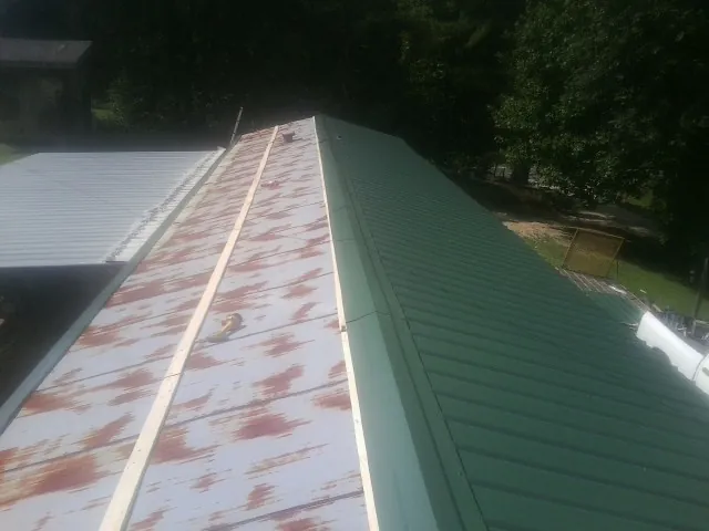 Old rusted panels beside newly installed green metal roofing — Wind Damage Roof Repair by Roofing Brothers in Adairville