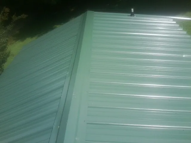 New green metal panels meeting at the ridge of a roof — Flat Roof Repair work by our crew in Adairville