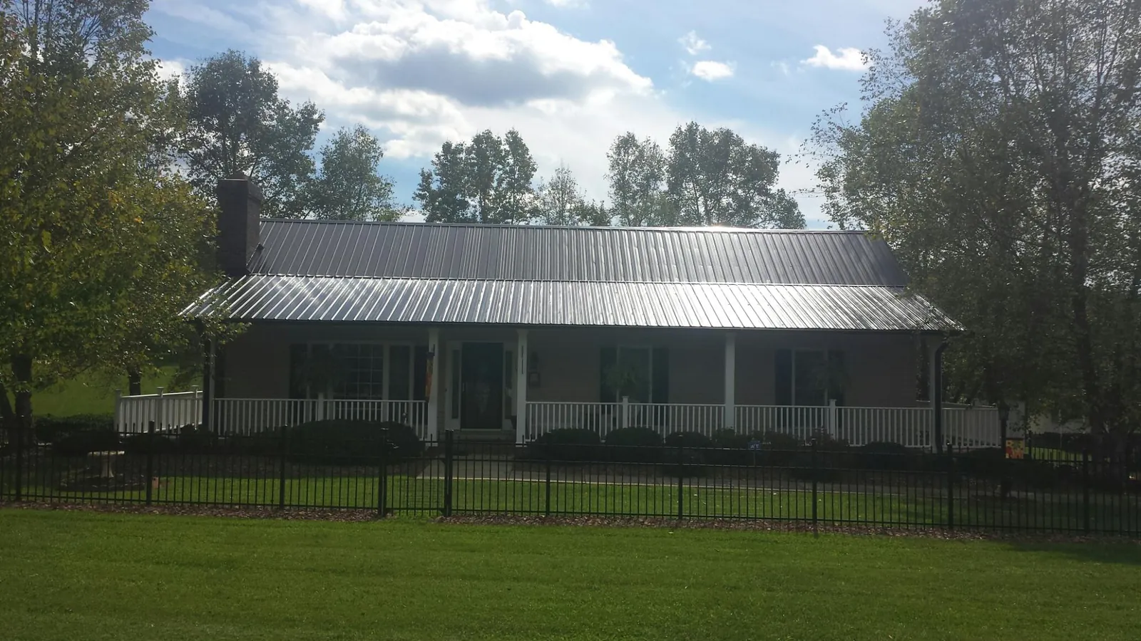 Gray metal roof on a brick ranch with a full width front porch — Gutter Guard Installation work by our crew in Adairville