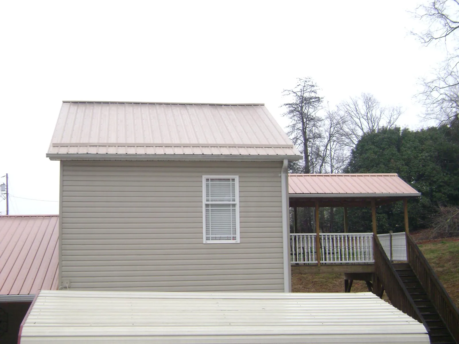 Tan metal roofs on a two story addition and attached porch, from a Roof Replacement job in Adairville